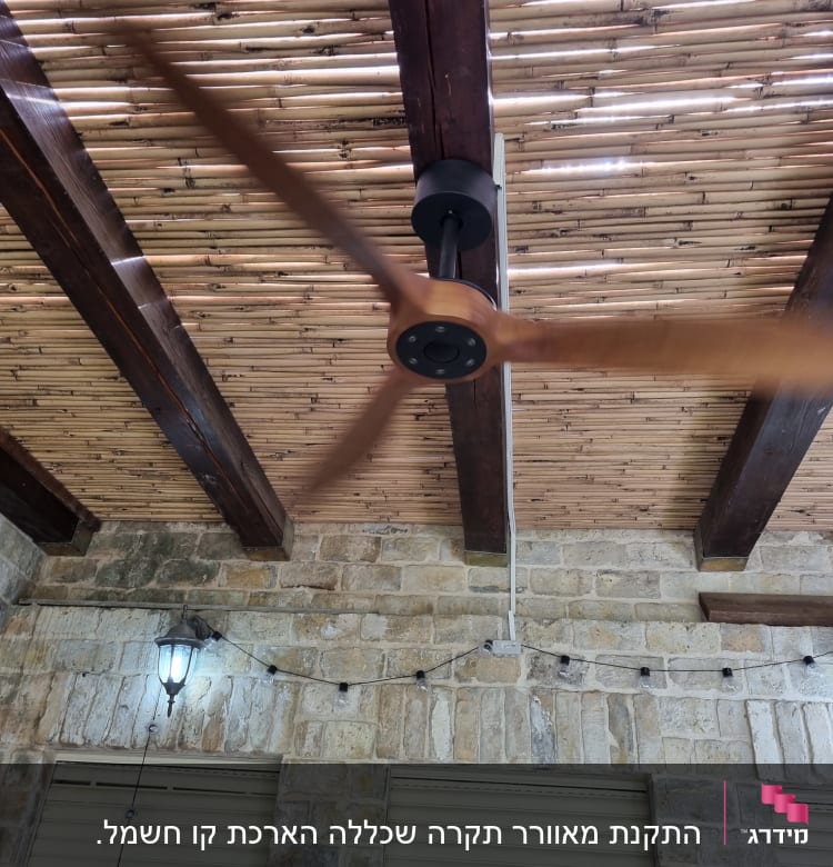 מאוורר תקרה מסתובב עם חוטי חשמל על קיר לבנים